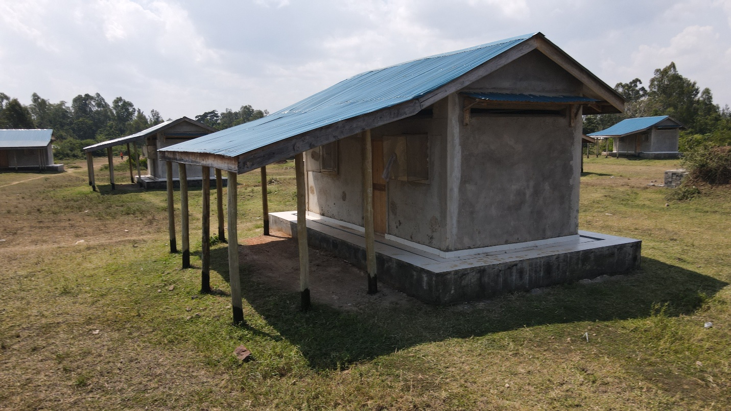 Experimental huts with blue metal roofs stand outdoors at the Rwambwa field station in western Kenya.